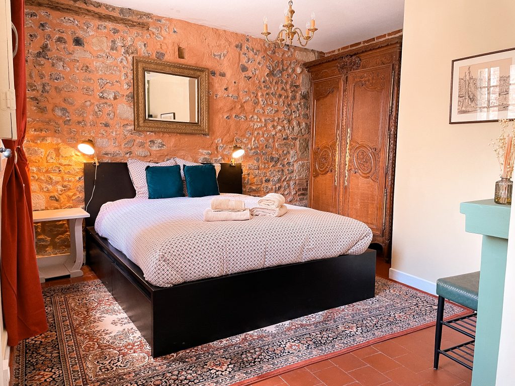 Lit double et murs en pierre de la chambre au rez-de-chaussée
