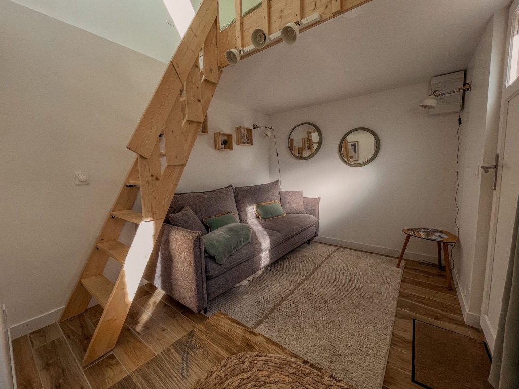 Coin salon du loft et escalier menant au couchage en mezzanine